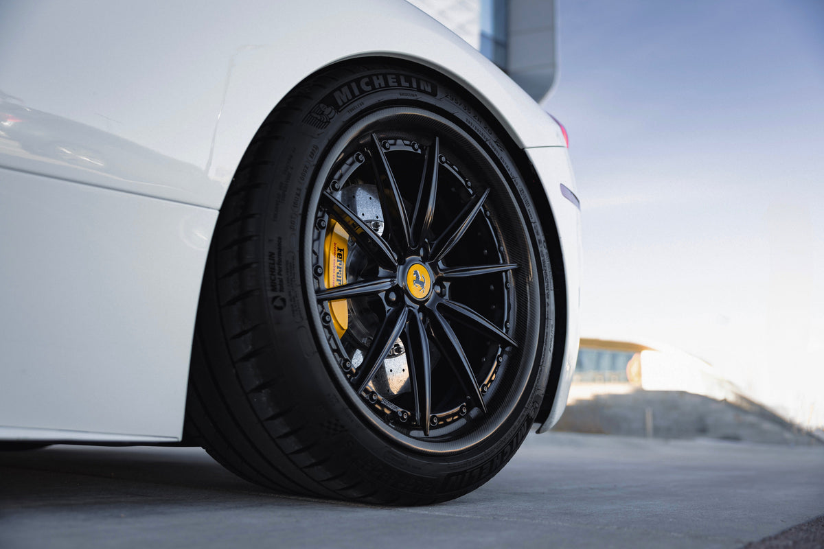 Black Stratix custom forged wheel with yellow brake caliper on a white Ferrari